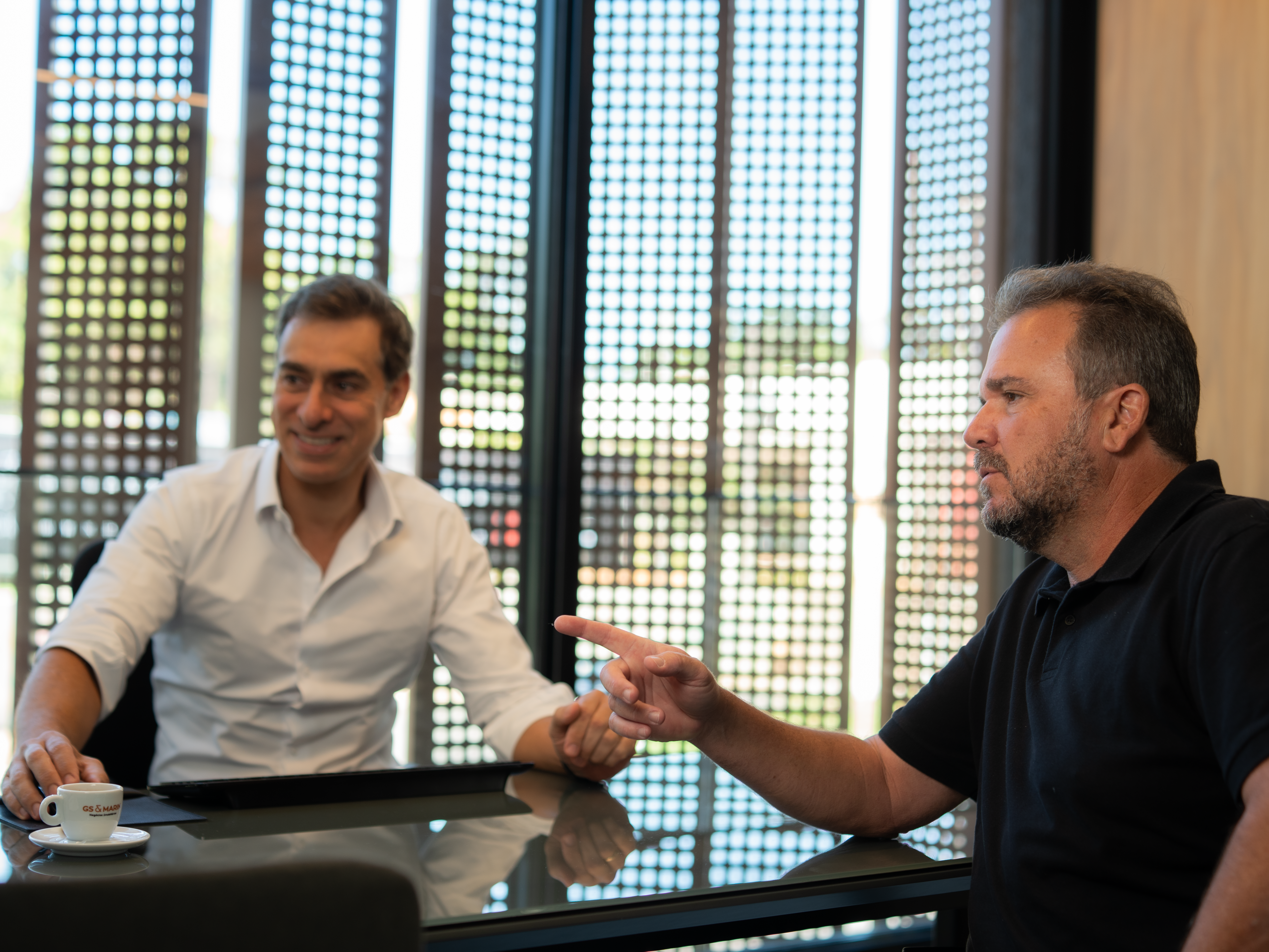 Sócios GS&MARIN: Fábio Marin e Gabriel Spagnuolo revisando contratos de compra e venda de imóvel de luxo sobre mesa de escritório.
